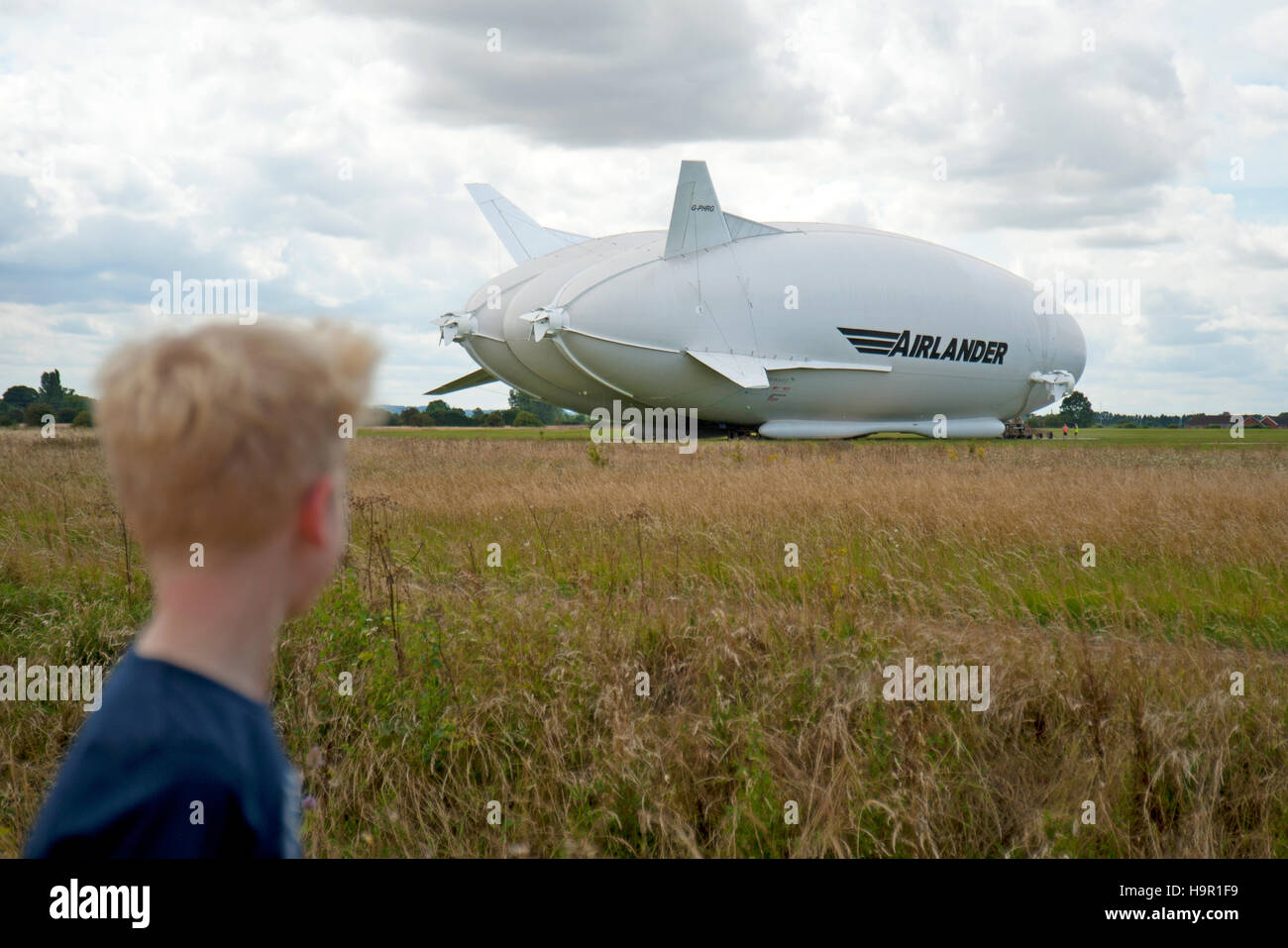 A boy looks on as the worlds largest aircraft, Airlander 10, is prepared for it's maiden flight from Cardington Airfield, Bedfordshire, England, UK Stock Photo