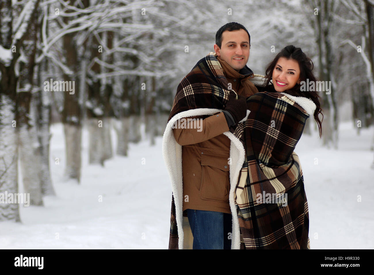 beautiful young couple in a snowy park wrapped Stock Photo - Alamy