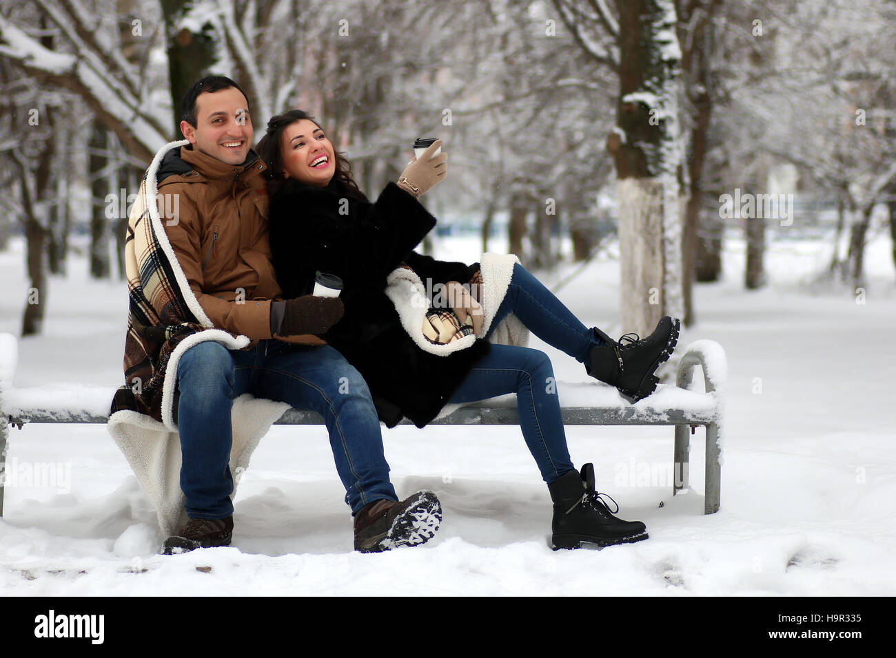 beautiful young couple in a snowy park wrapped Stock Photo - Alamy