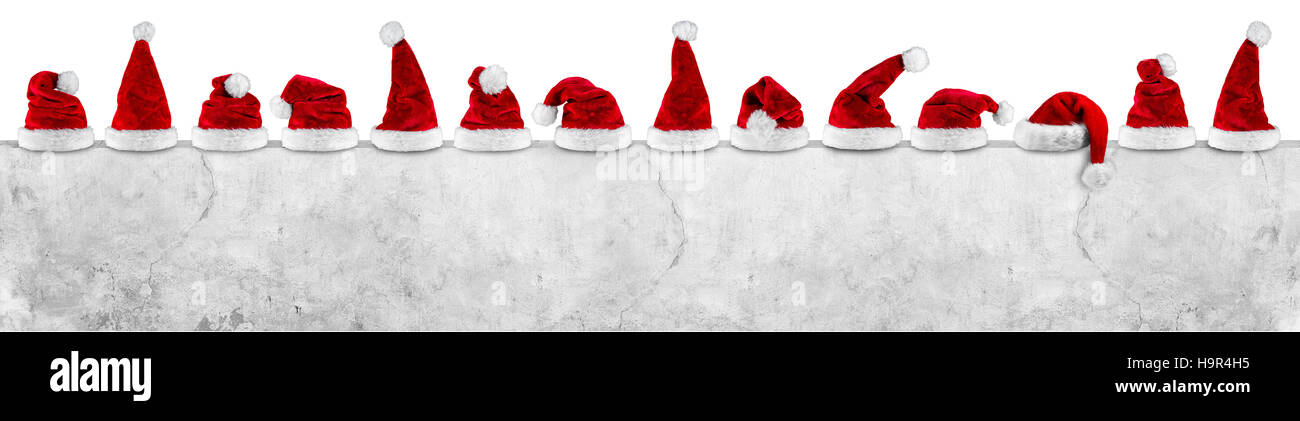 row of red white plush santa claus christmas xmas hat on  empty concrete wall billboard isolated background Stock Photo