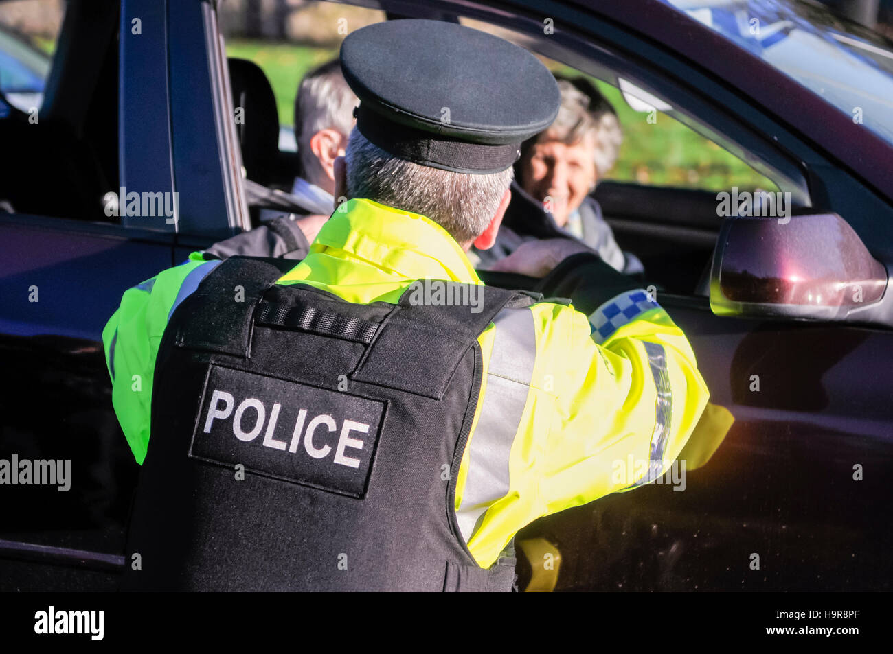 Belfast, Northern Ireland. 24 Nov 2016 - A PSNI officer talks to an elderly driver as he stops traffic to perform a random driver check. Credit:  Stephen Barnes/Alamy Live News Stock Photo