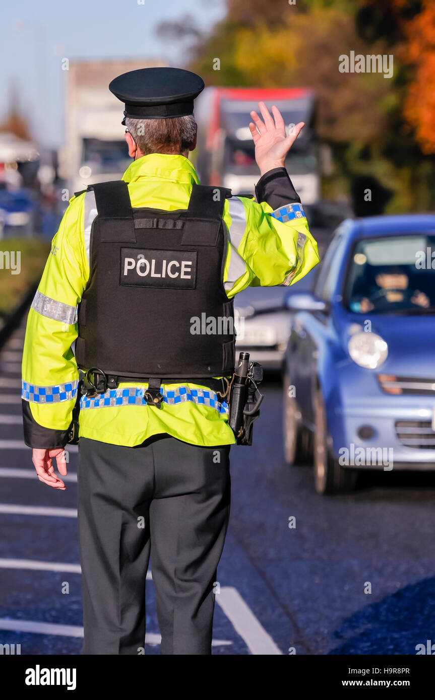 Belfast, Northern Ireland. 24 Nov 2016 - An armed PSNI officer waves on traffic during a vehicle checkpoint. Credit:  Stephen Barnes/Alamy Live News Stock Photo