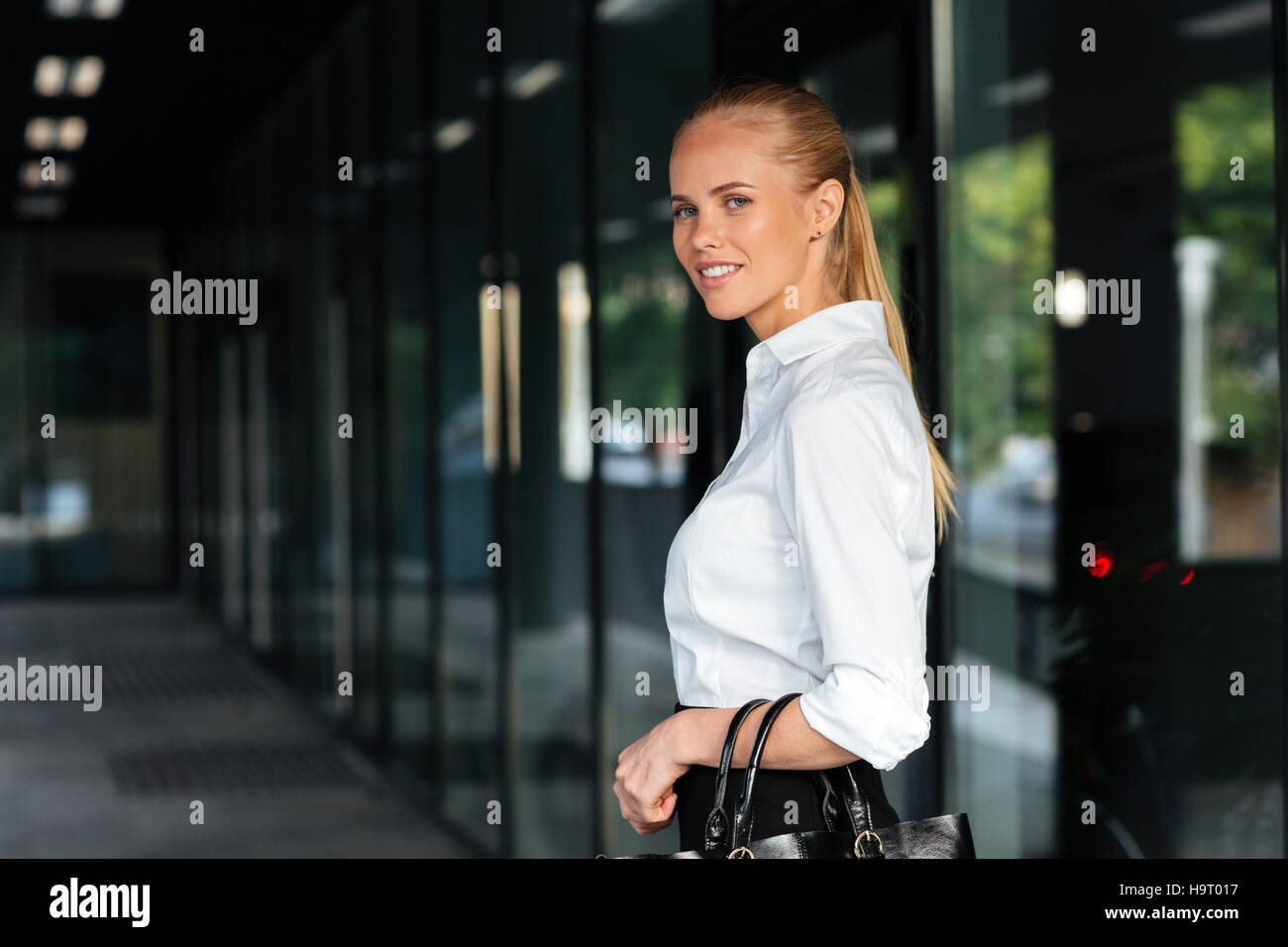 Happy smiling businesswoman standing and holing handbag outdoors Stock Photo
