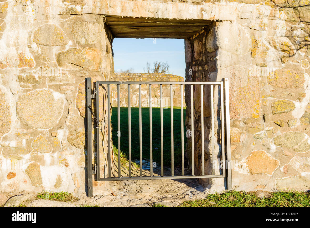 Closed metal gate in stone wall passage. Stock Photo