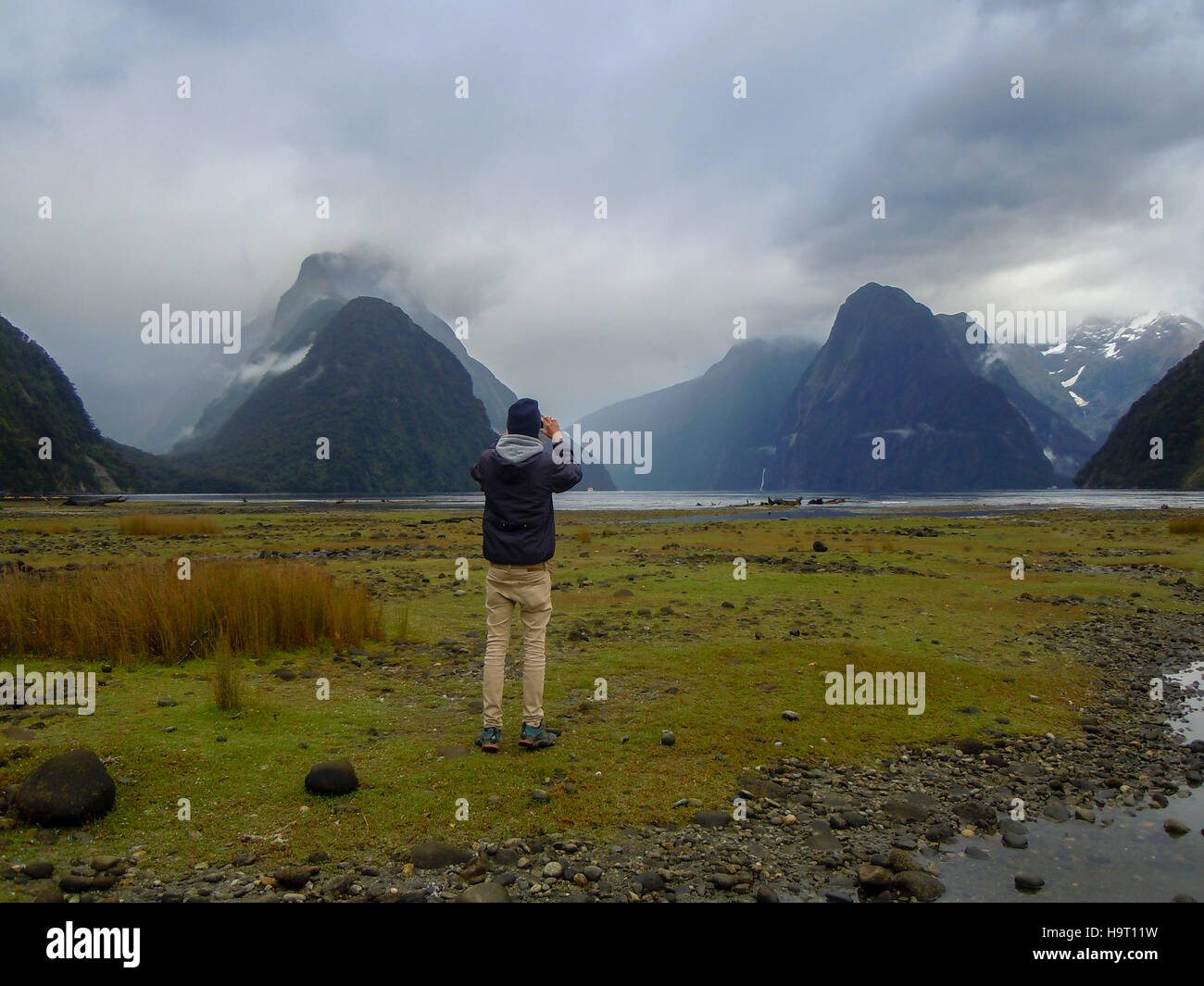 Young backpacker take a picture at Milford Sound, Fiordland National
