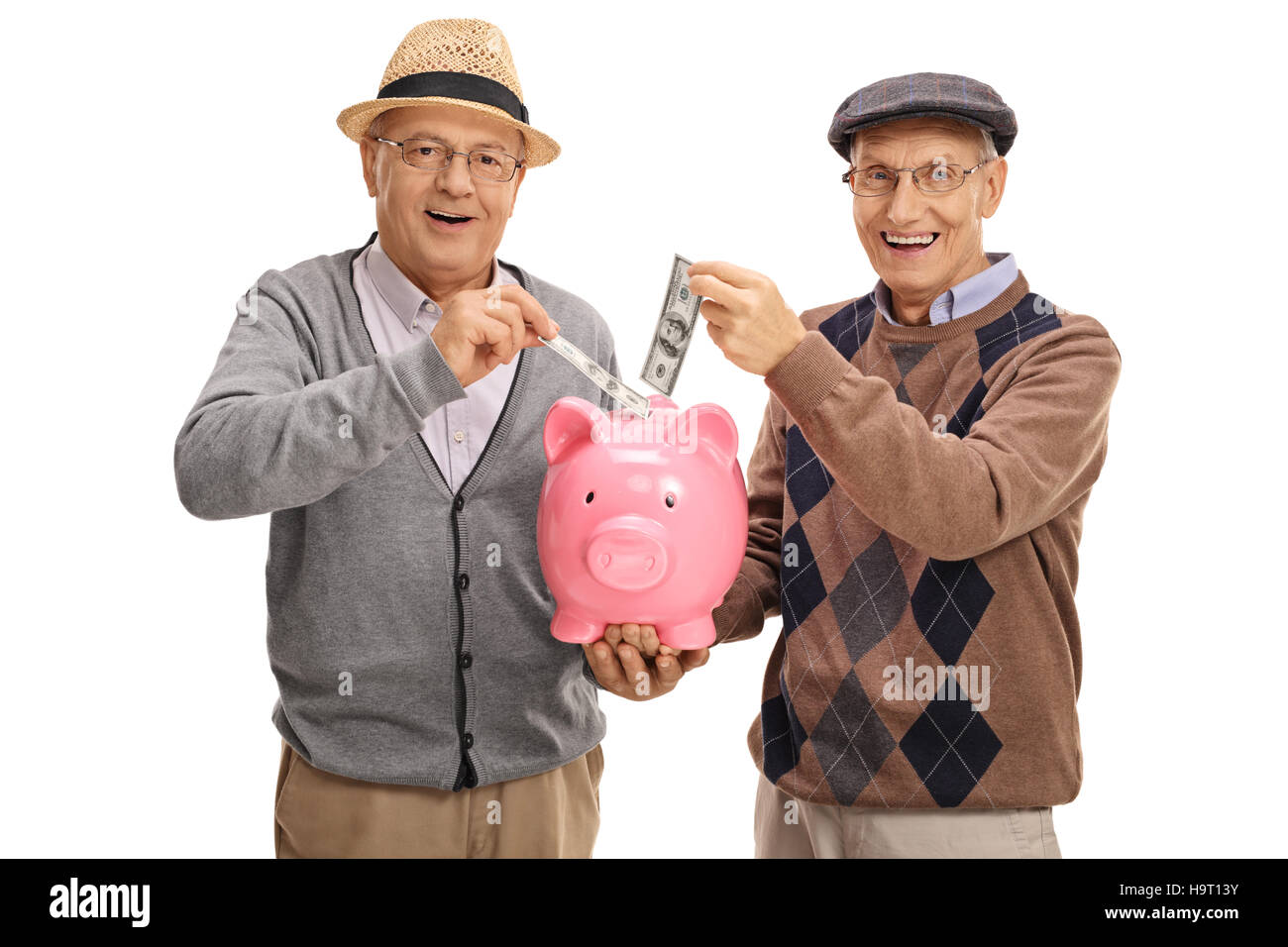 Seniors putting money in a piggybank and looking at the camera isolated on white background Stock Photo