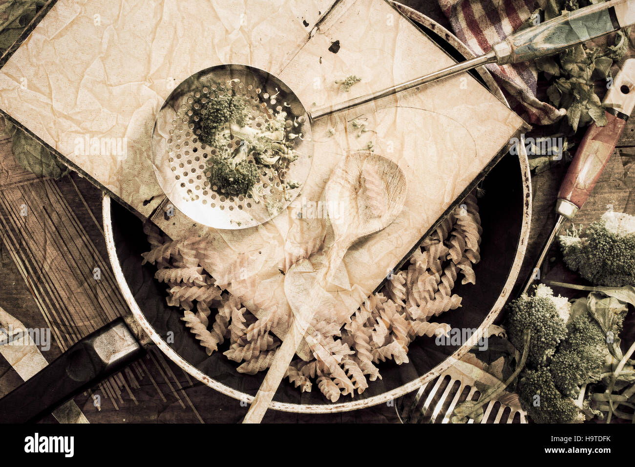Cooking book with spoon, noodles and broccoli in frying pan - vintage textured retro image, arranged on an old wooden table Stock Photo