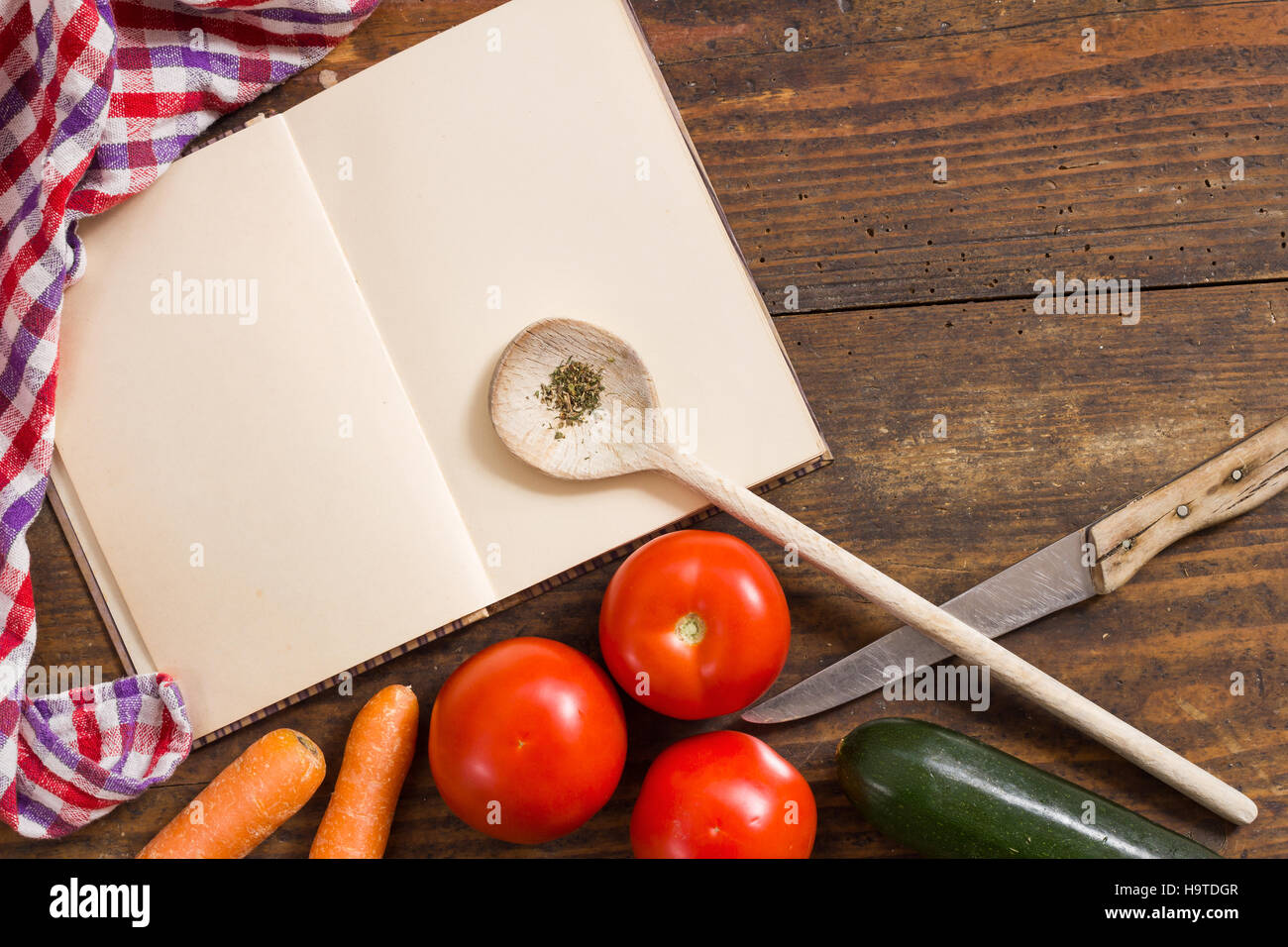 Opened cookbook and kitchen cloth, cooking utensils and vegetables as still life and top view background image with copy space Stock Photo