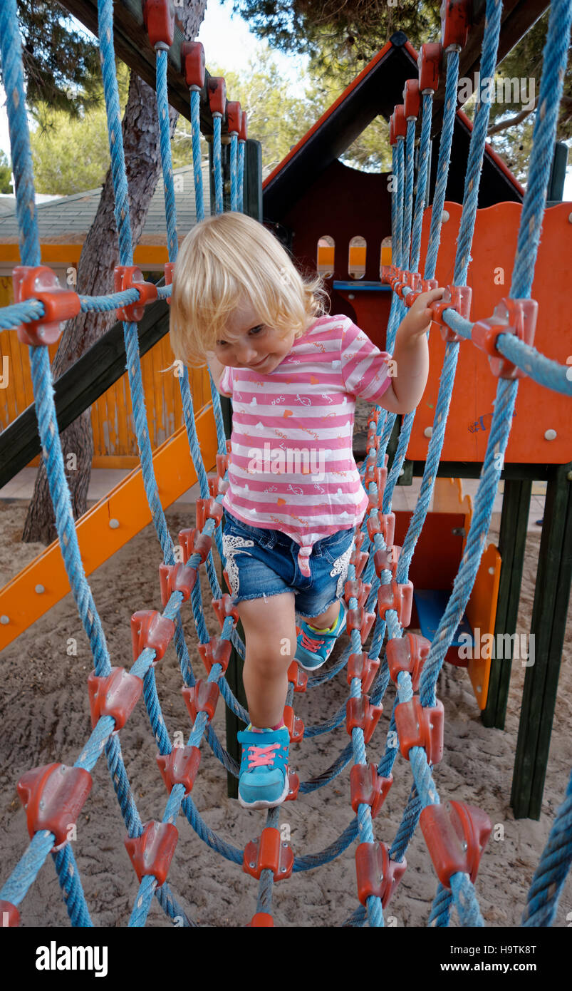 Two year old girl climbing rope bridge, playground, Formentera Island, Balearic Islands, Spain Stock Photo