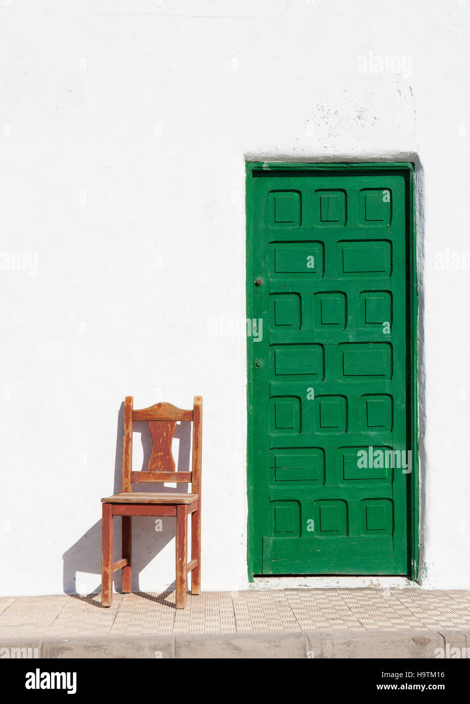 Green door with wooden chair in front of white house wall, El Puerto de la Cruz, Peninsula Jandia, Fuerteventura, Canary Islands Stock Photo