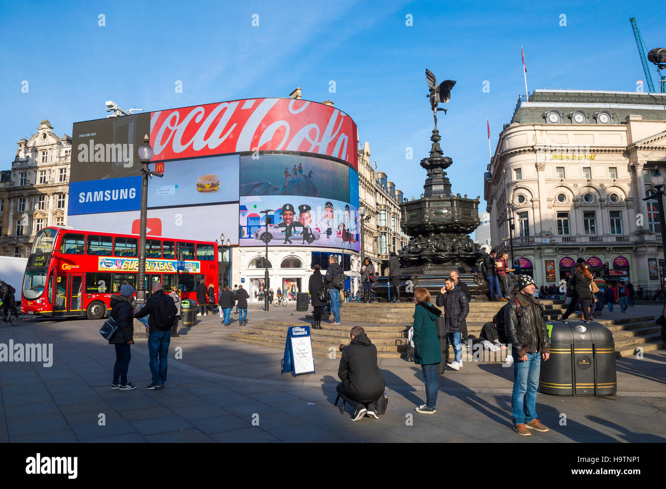 LONDON - NOVEMBER 11, 2016: Pedestrians and double-decker buses pass the flashing signs of Piccadilly Circus on a bright morning Stock Photo