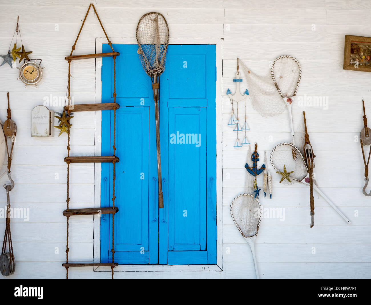 Beach fishing decoration in a white wall with blue window Stock Photo