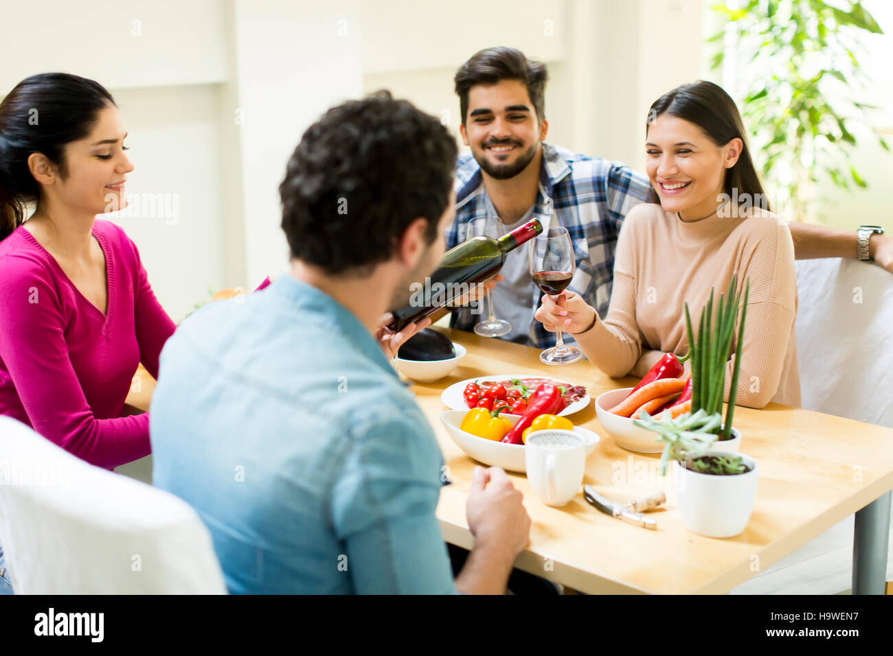 Group of happy young people sitting by the table eating and drinking red wine Stock Photo Alamy