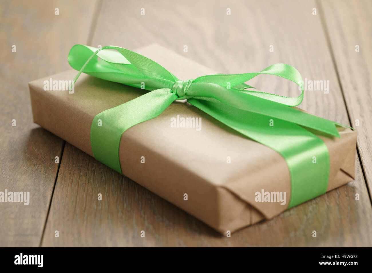 rustic craft paper gift box with green ribbon bow on wood table Stock Photo