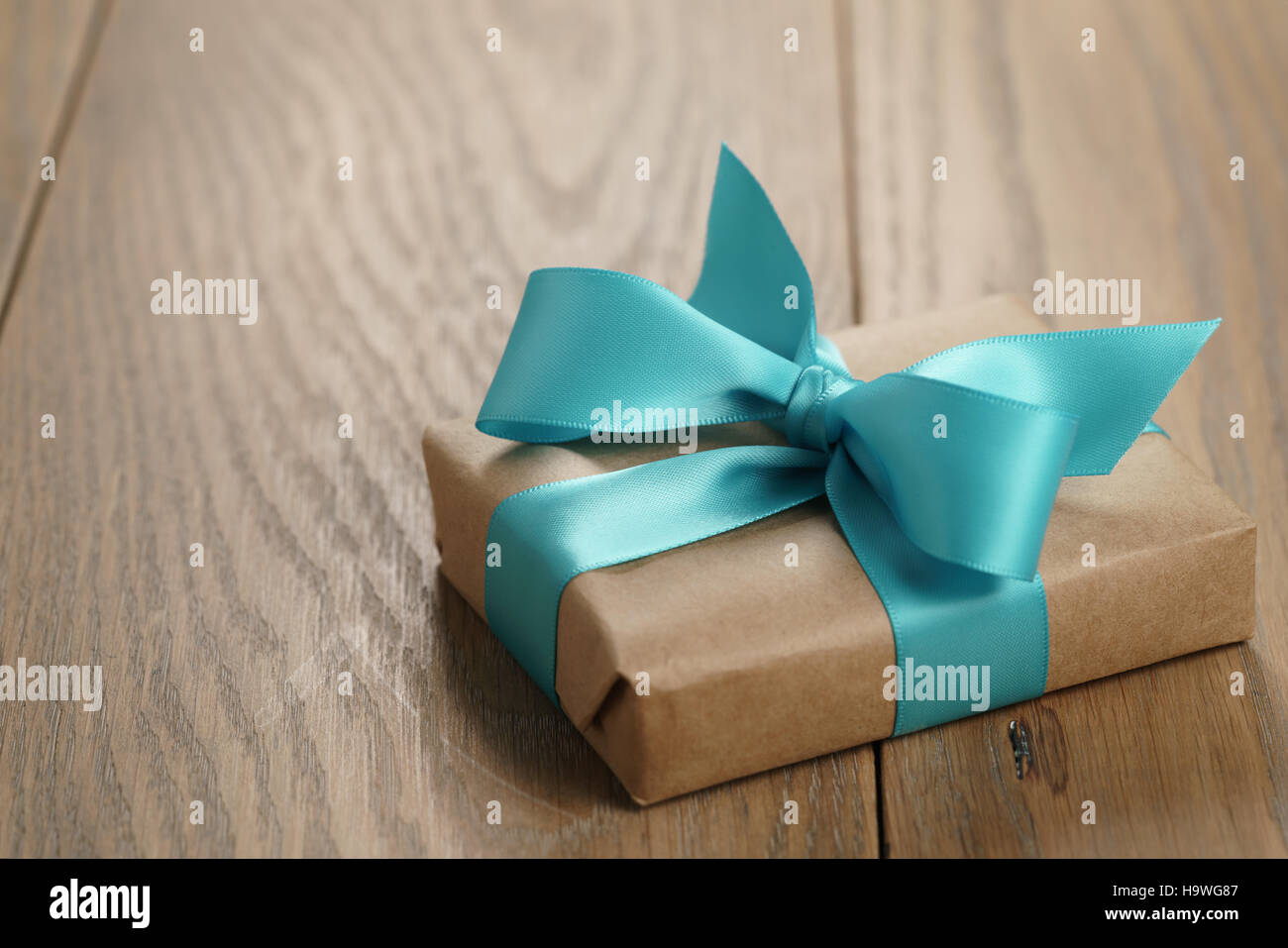 rustic craft paper gift box with blue ribbon bow on wood table Stock Photo