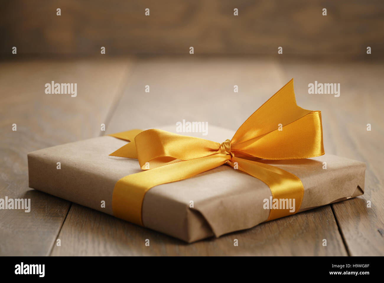 rustic craft paper gift box with orange ribbon bow on wood table Stock Photo