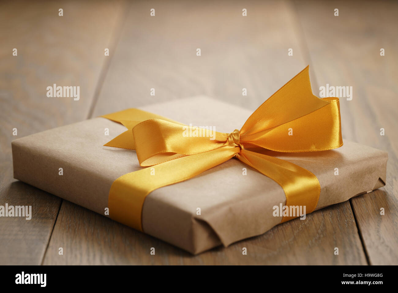 rustic craft paper gift box with orange ribbon bow on wood table Stock Photo