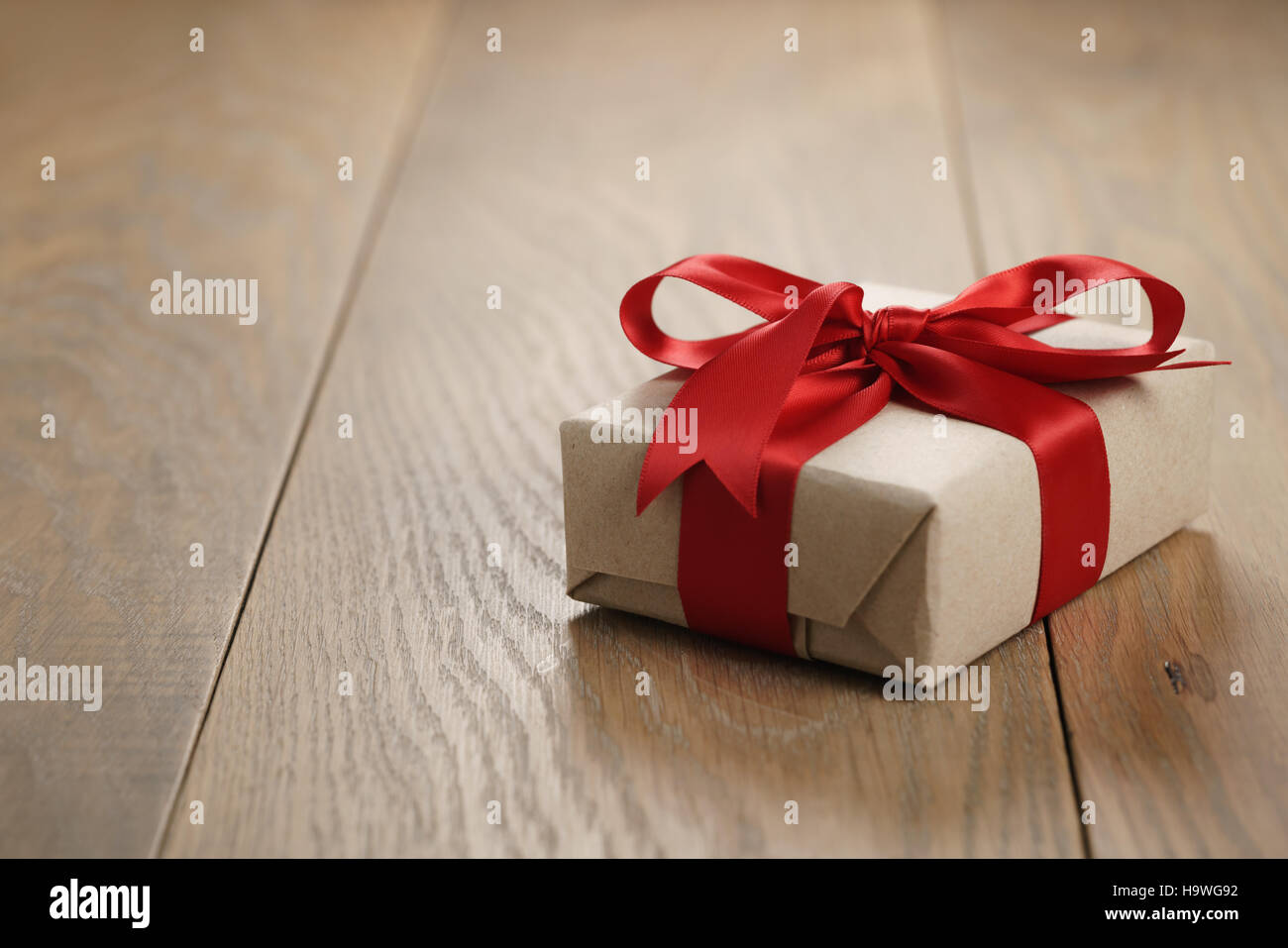rustic craft paper gift box with red ribbon bow on wood table Stock Photo