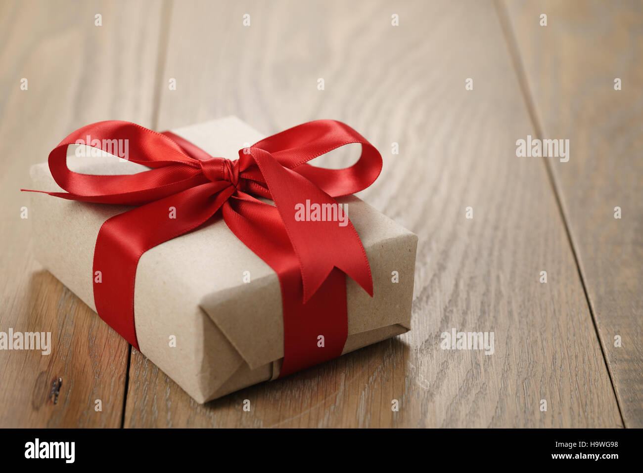 rustic craft paper gift box with red ribbon bow on wood table Stock Photo