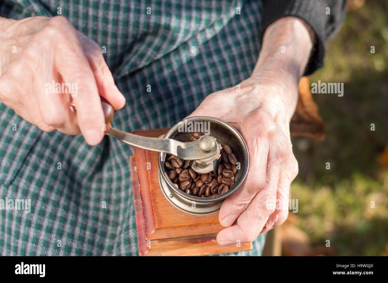 Senior woman grinding coffee on a vintage coffee grinder Stock Photo