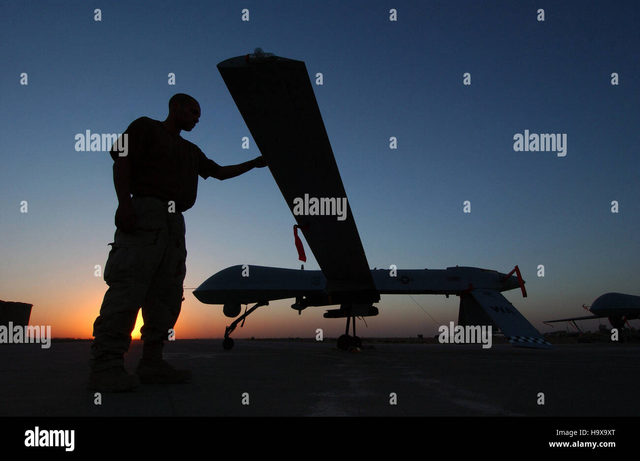 U.S. soldiers inspect an RQ-1 Predator unmanned aerial vehicle at sunset after a flight mission for Operation Iraqi Freedom at the Balad Air Base September 15, 2004 in Yathrib, Iraq. Stock Photo