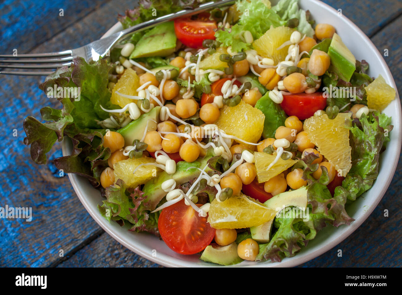 Healthy green salad with orange, avocado, tomatoes, sprouts of mung