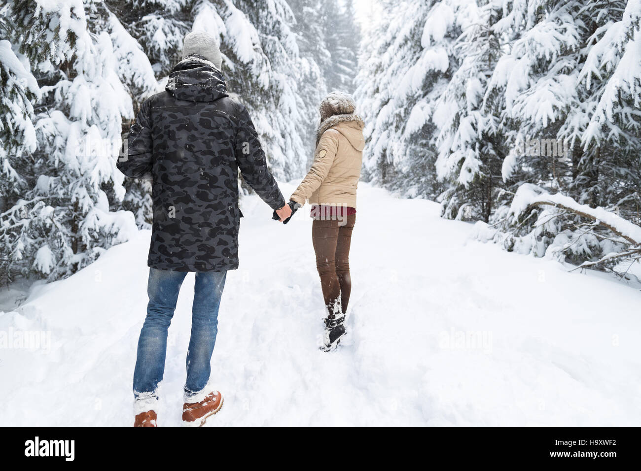 Young Couple Walking In Snow Forest Outdoor Man And Woman Holding Hands ...