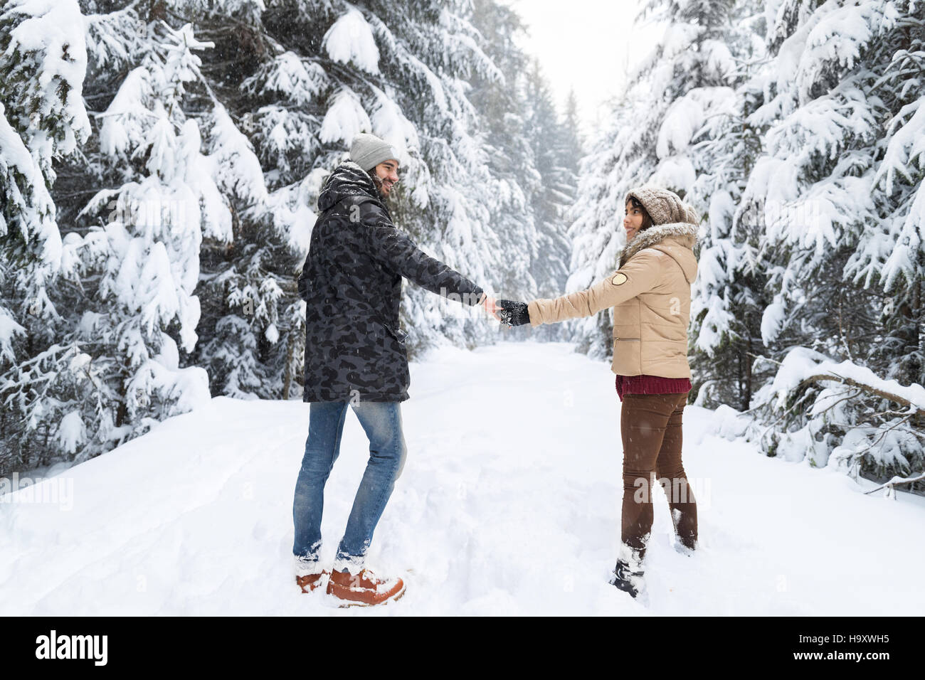 Young Couple Walking In Snow Forest Outdoor Man And Woman Holding Hands ...