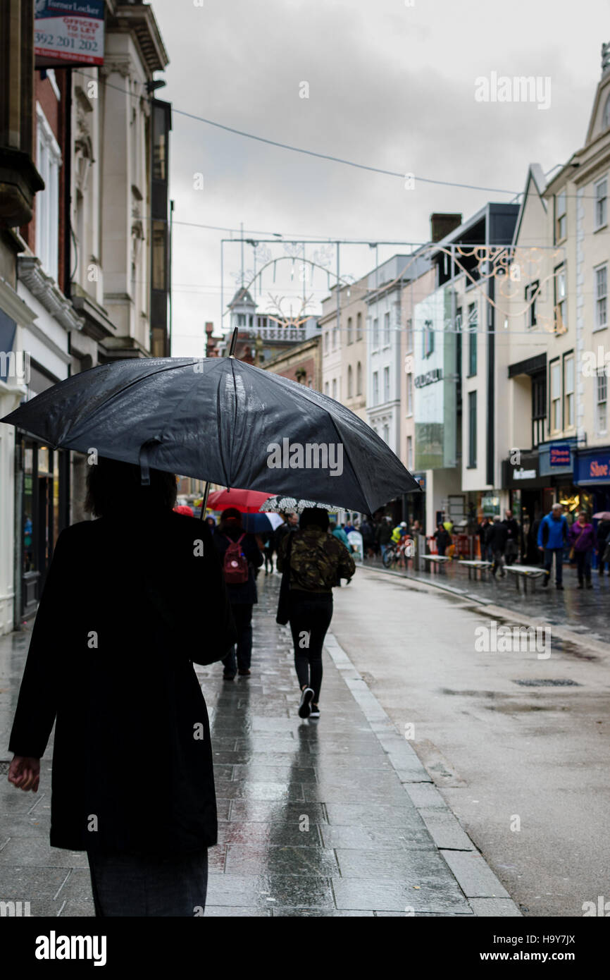 Exeter, England, UK - 22 November 2016: Unidentified people walk on High Street in typical British rainy weather. Stock Photo