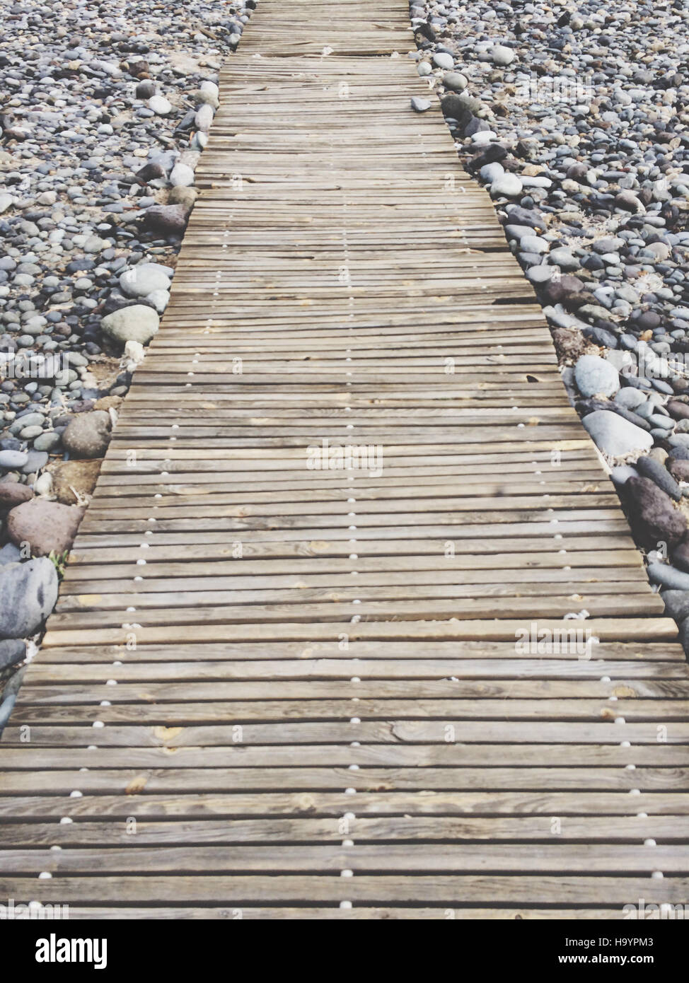 wooden pier on pebble stones Stock Photo
