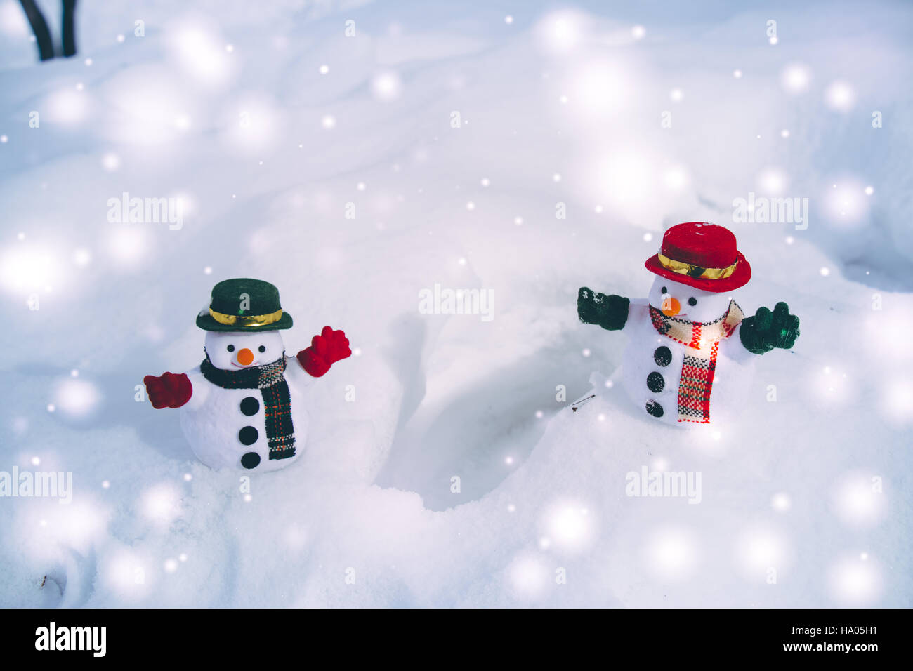 Snowman and friend stand among pile of snow in park. Morning