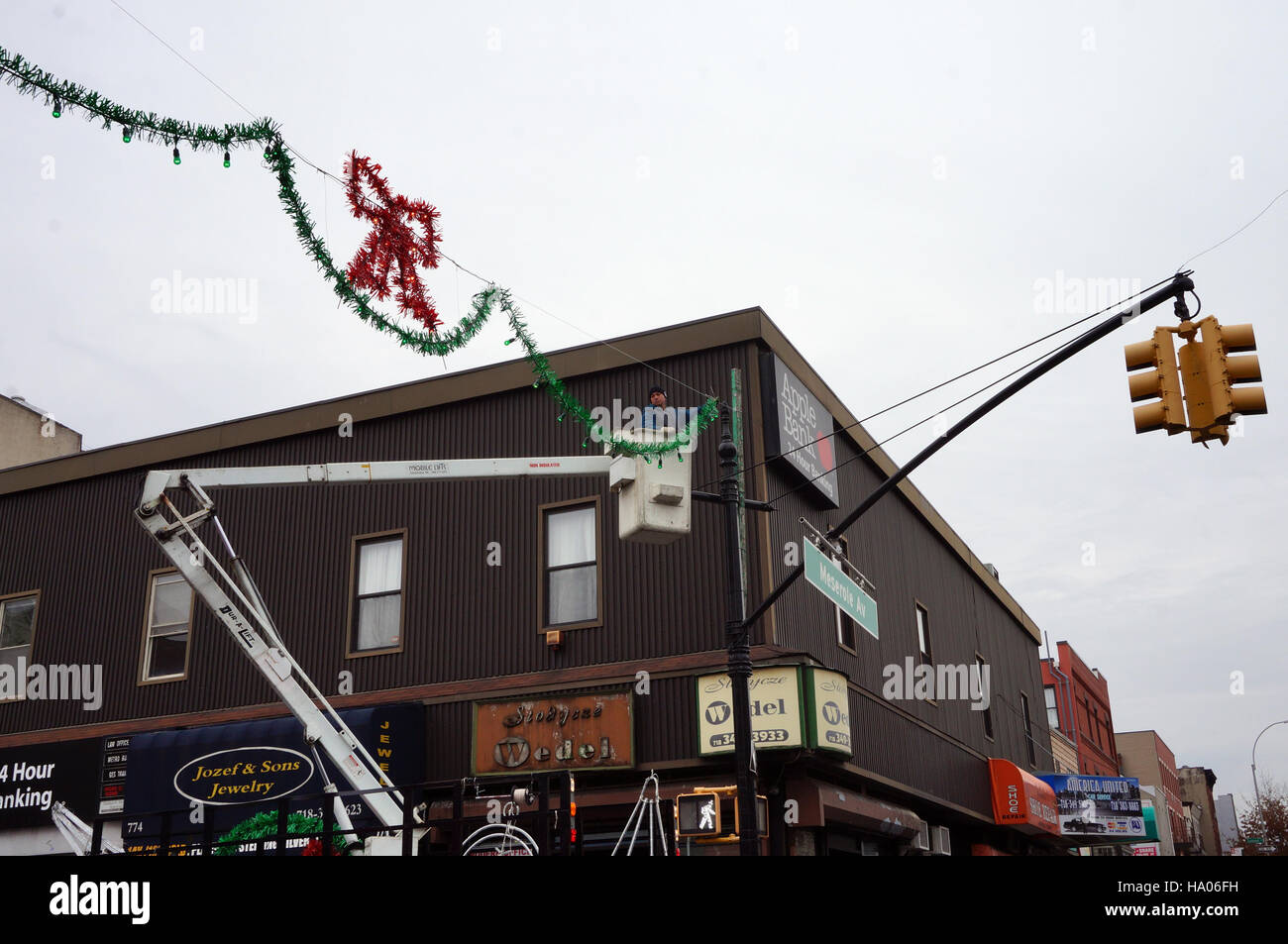 Man in Bucket Truck Putting Up Christmas Decorations on City Street Stock Photo