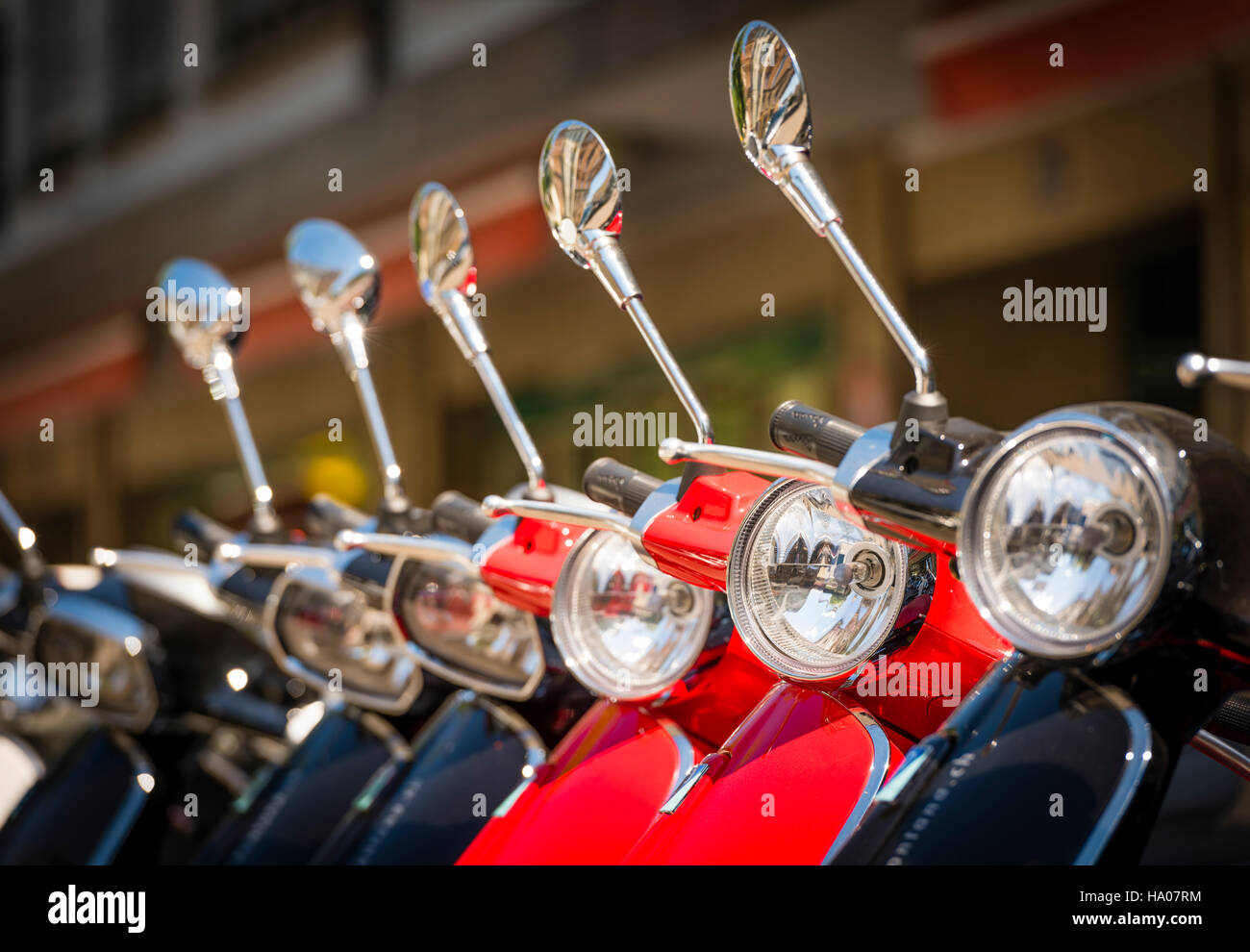 Many bright colorful Vespa motor scooters are lined up outside on a sunny street in Zurich, Switzerland Stock Photo