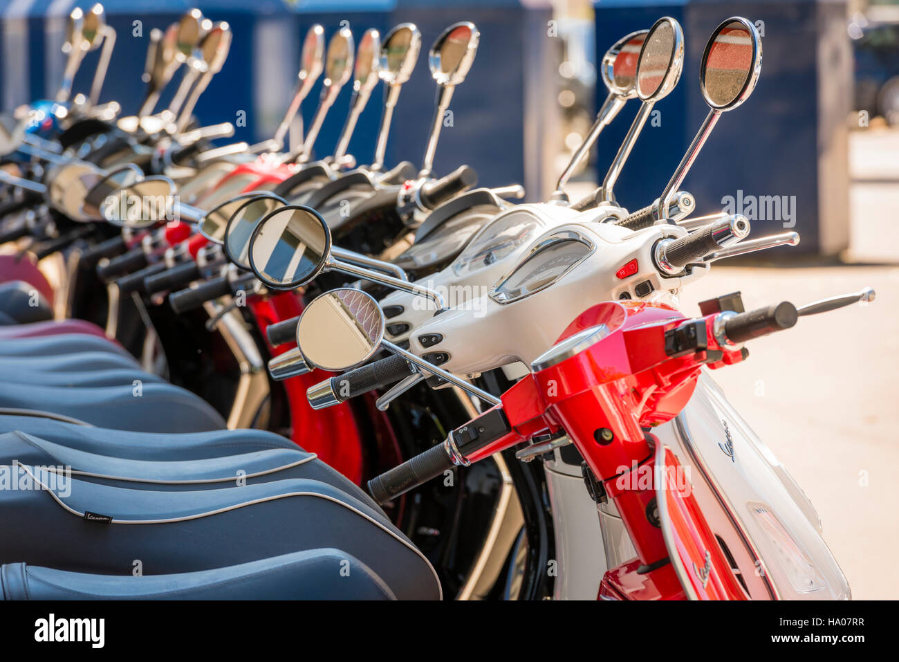 Many bright colorful Vespa motor scooters are lined up outside on a sunny street in Zurich, Switzerland Stock Photo