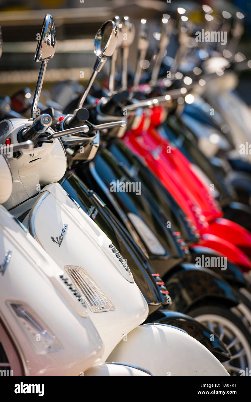 Many bright colorful Vespa motor scooters are lined up outside on a sunny street in Zurich, Switzerland Stock Photo