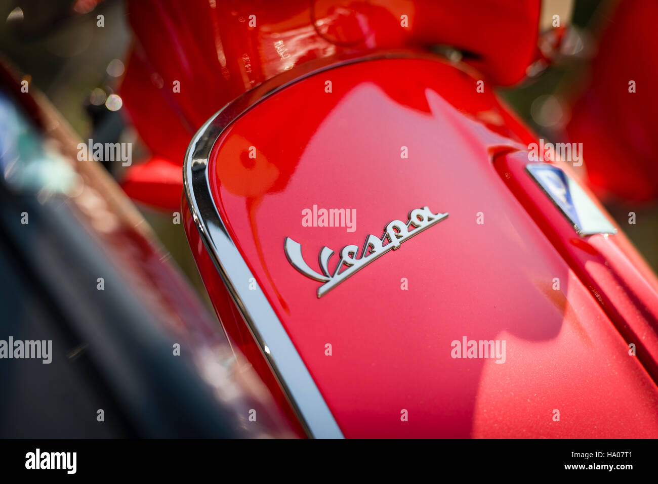 Close-up of the Vespa logo on a bright red Vespa motor scooter parked outside on a street in the sun Stock Photo