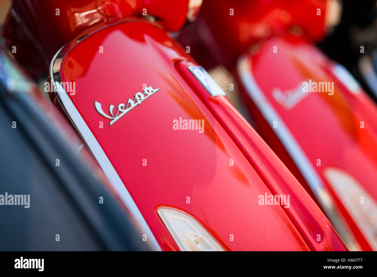 Close-up of the Vespa logo on a bright red Vespa motor scooter parked outside on a street in the sun Stock Photo