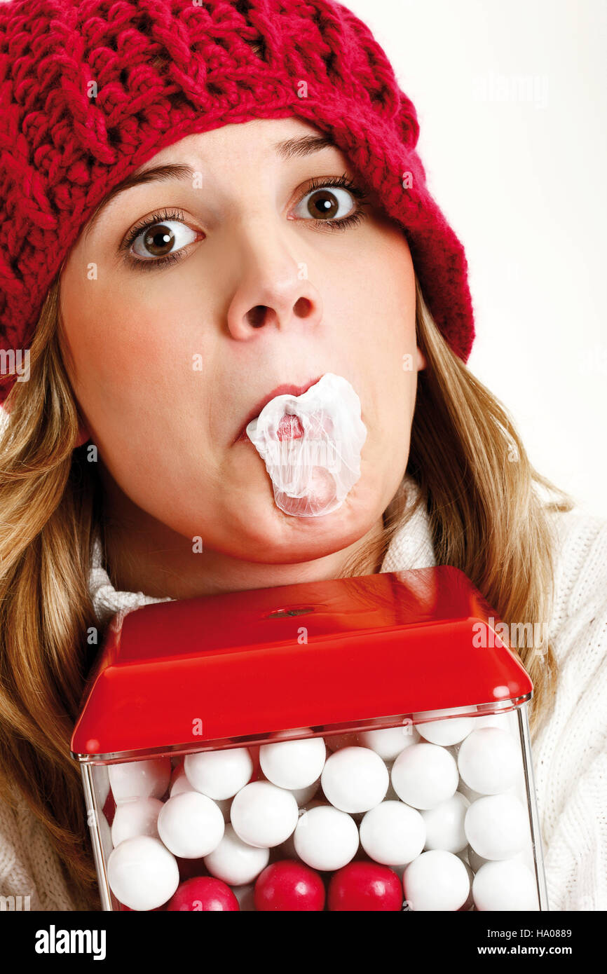 Young woman with a popped bubble of bubble gum behind a gumball machine Stock Photo