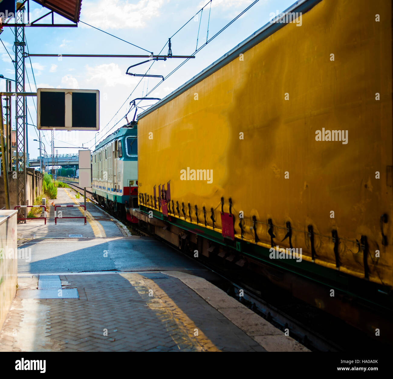 passing freight train at a small station pulled by a locomotive Stock Photo