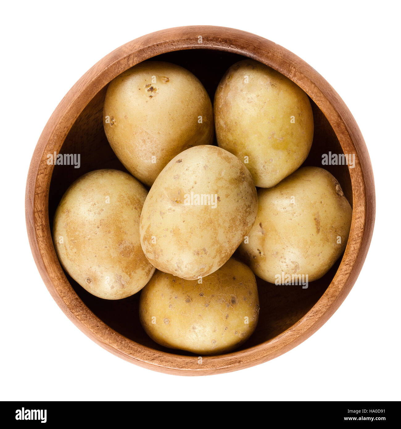 Raw mini potatoes in wooden bowl. Edible tuber of nightshade Solanum tuberosum, a starchy crop. Isolated macro food photo. Stock Photo