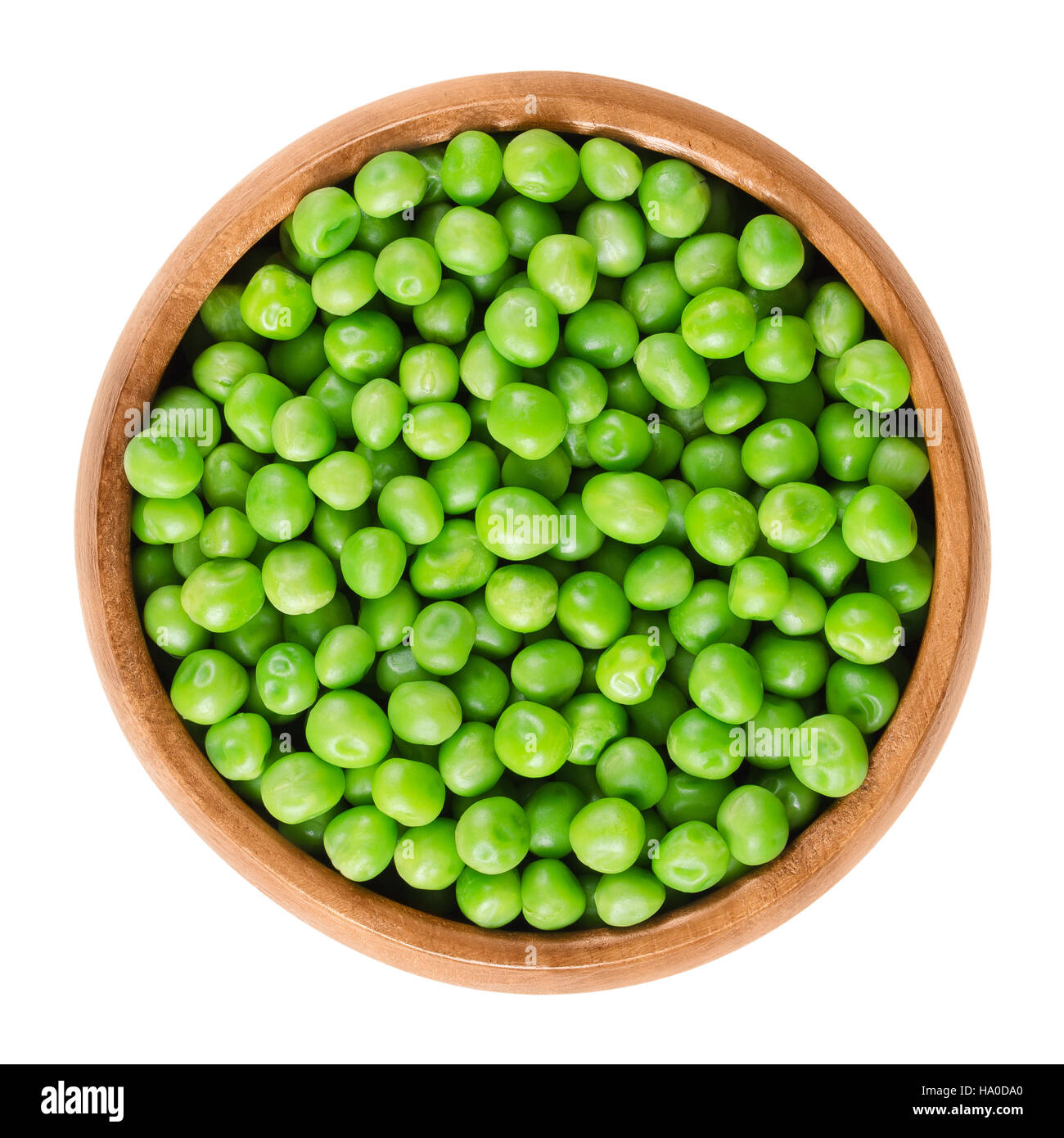 Raw peas in wooden bowl. Green small spherical seeds of the pod fruit Pisum sativum, an edible legume. Isolated macro food photo Stock Photo