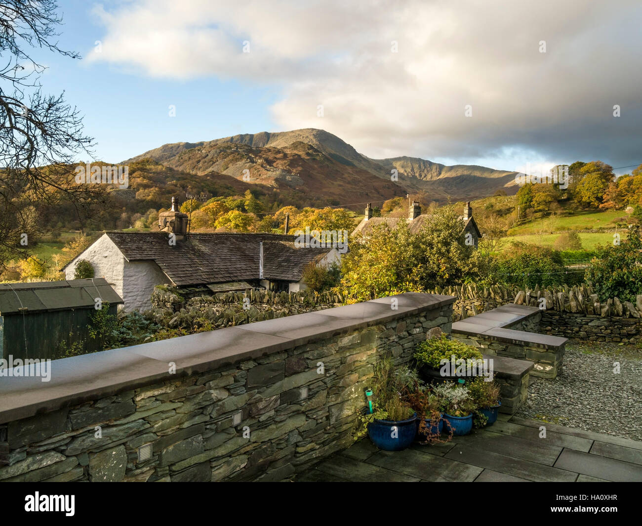 Dry stone wall and cottages in Little Langdale with Wetherlam beyond, English Lake District, Cumbria, England, UK. Stock Photo