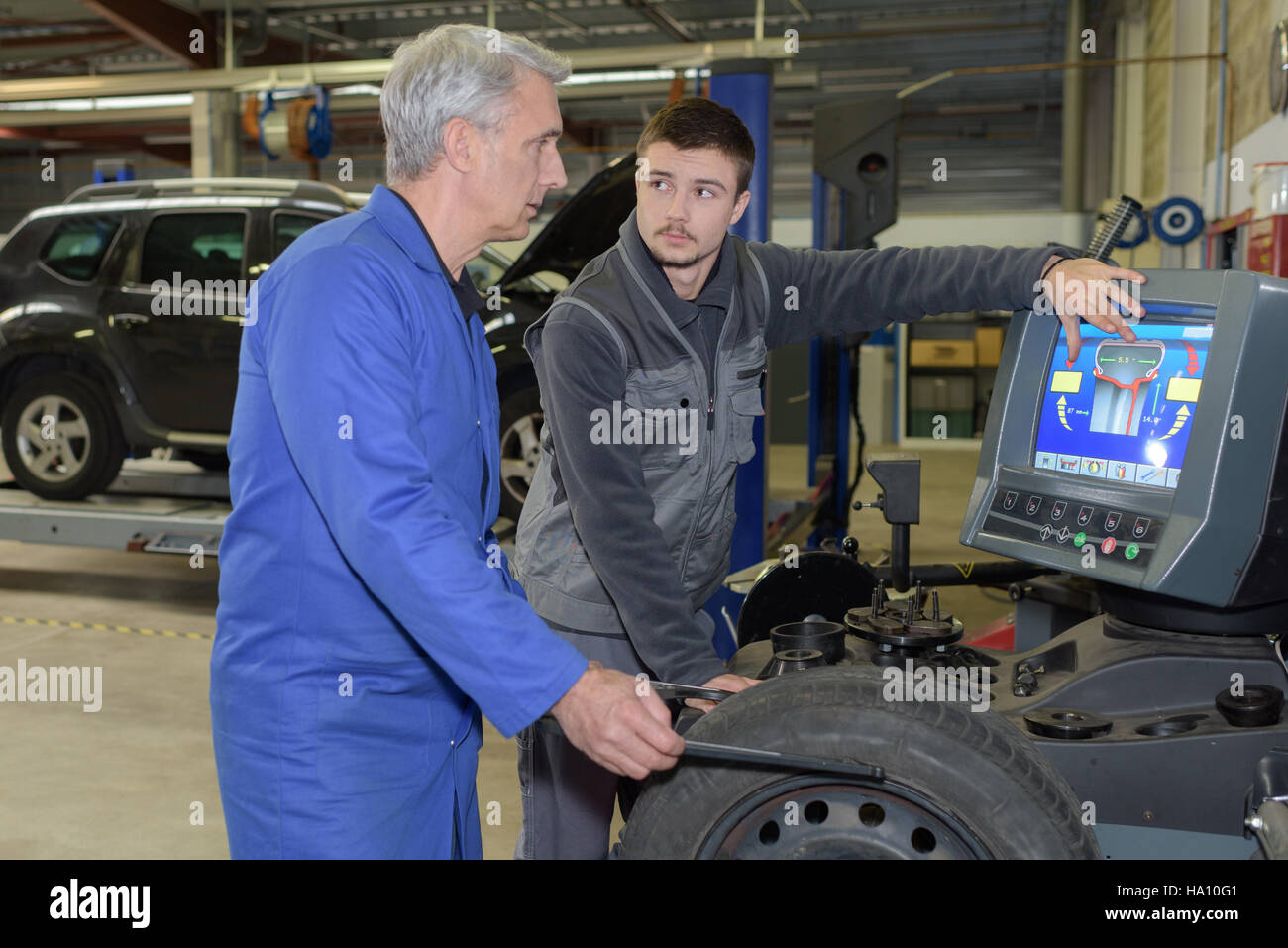 apprentice mechanic and teacher retreading wheel in automotive