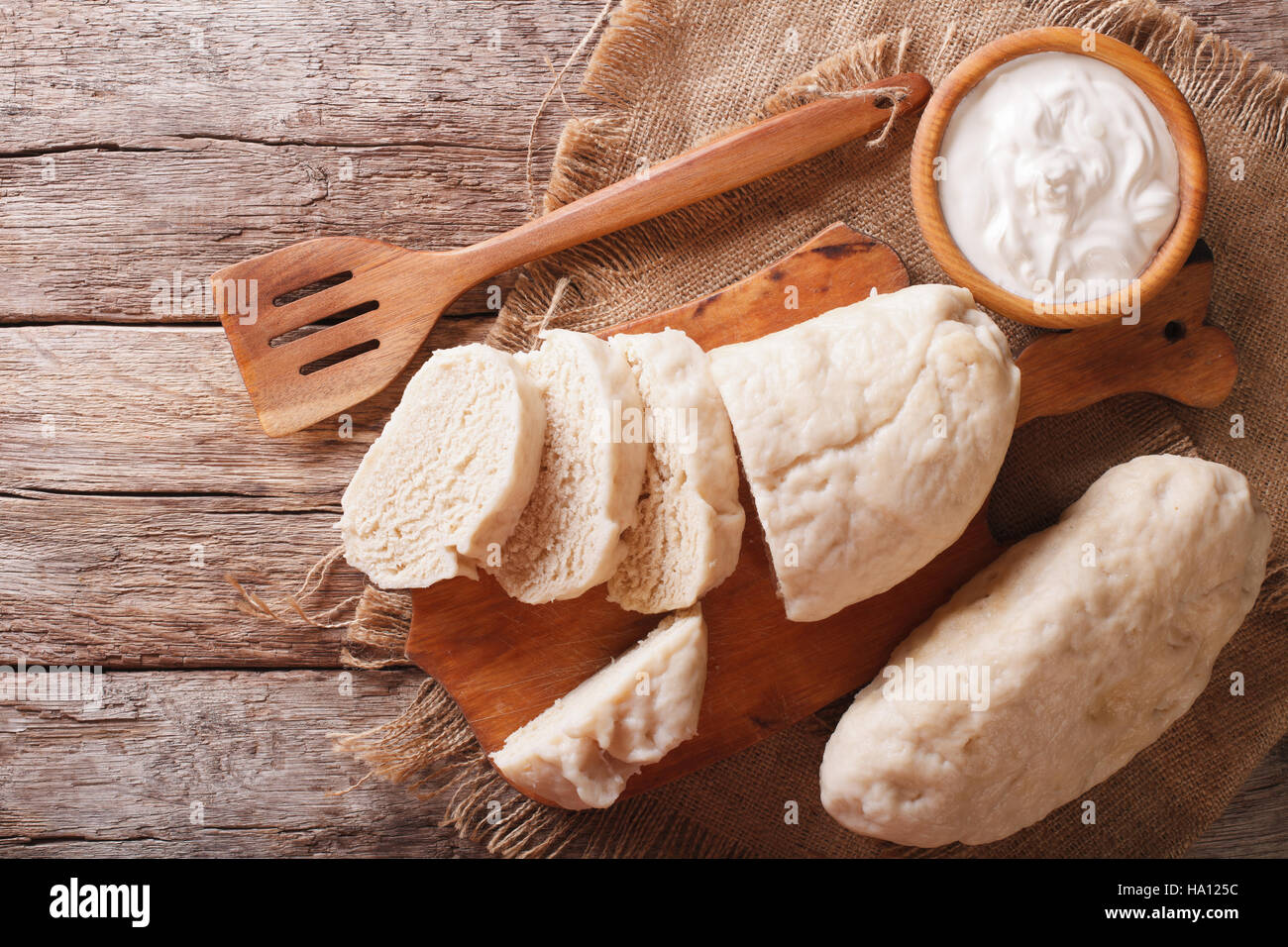 Czech cuisine: sliced boiled knedliks close-up on chopping board and sour cream. horizontal view from above Stock Photo
