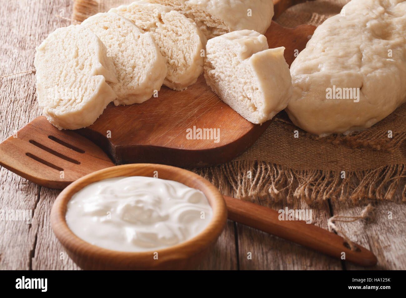 sliced boiled knedle close-up on chopping board and sour cream. horizontal Stock Photo