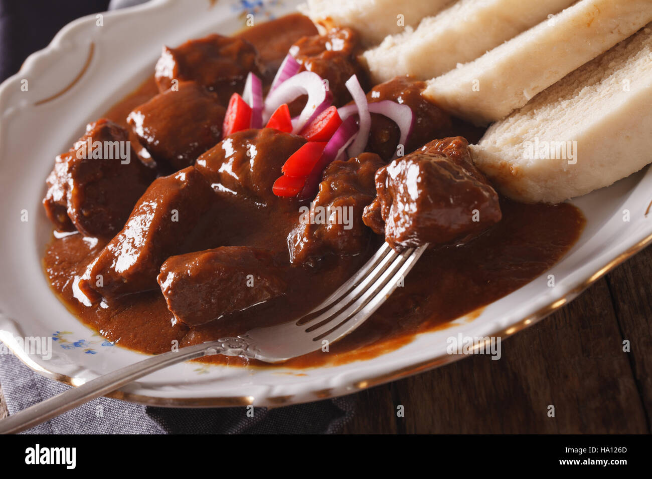Tasty hot Czech goulash with knedliks in a plate close-up. horizontal Stock Photo
