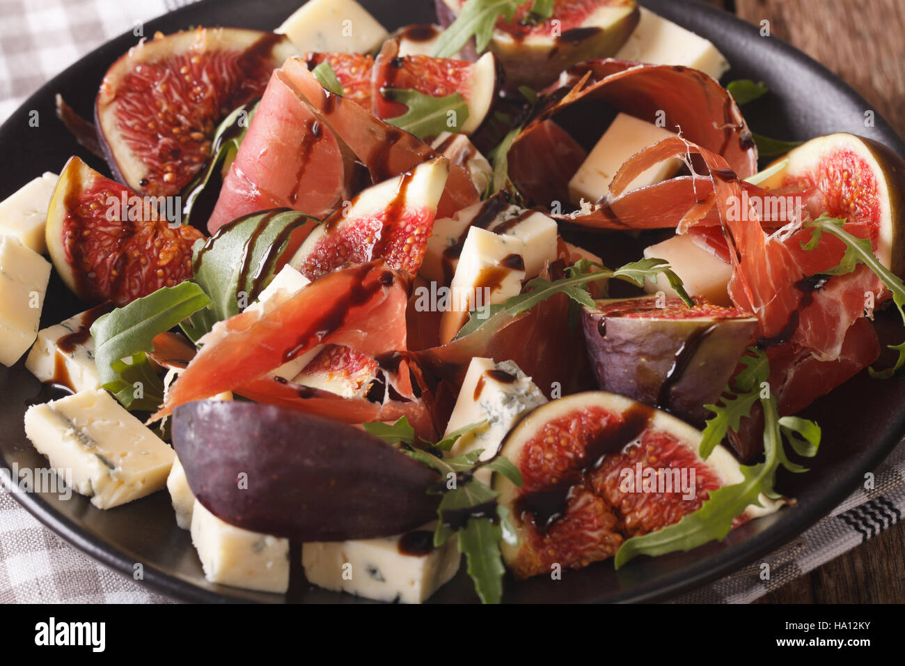 Salad with figs, prosciutto, cheese and arugula macro on a plate on the table. horizontal Stock Photo