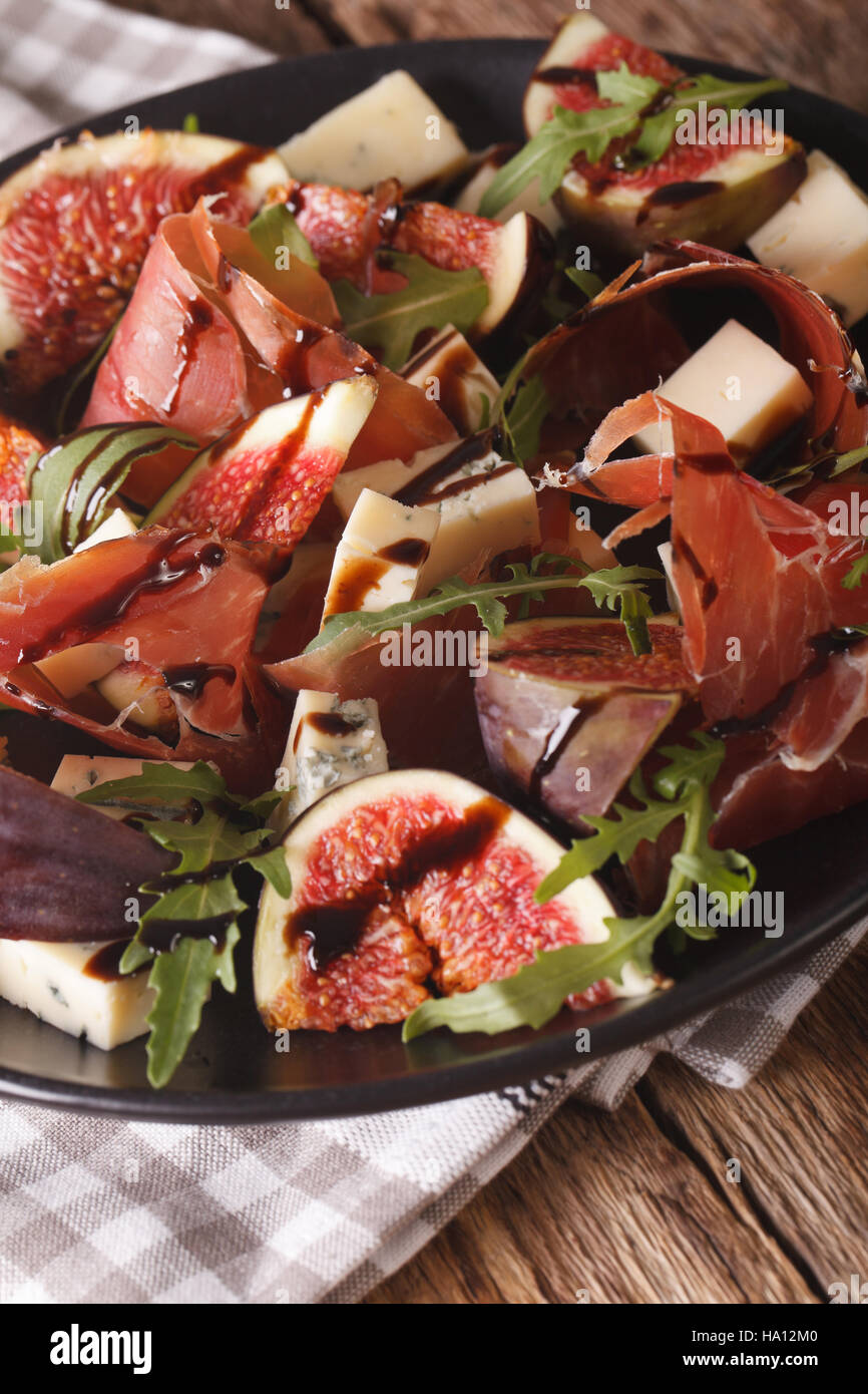 Salad with figs, prosciutto, cheese and arugula close-up on a plate on the table. vertical Stock Photo