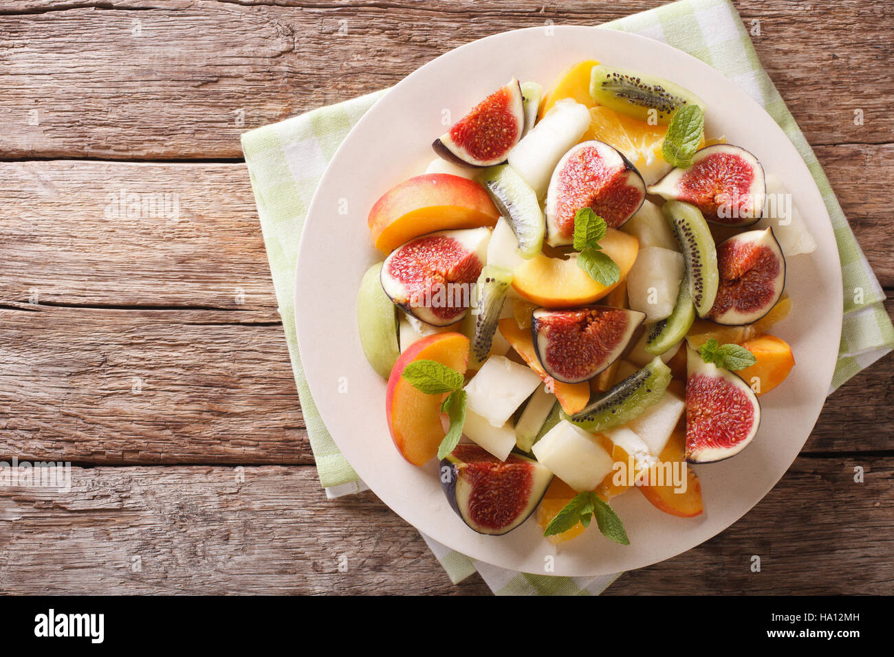 Healthy Fruit salad with fig, peach, melon, kiwi and orange close-up on the table. horizontal view from above Stock Photo