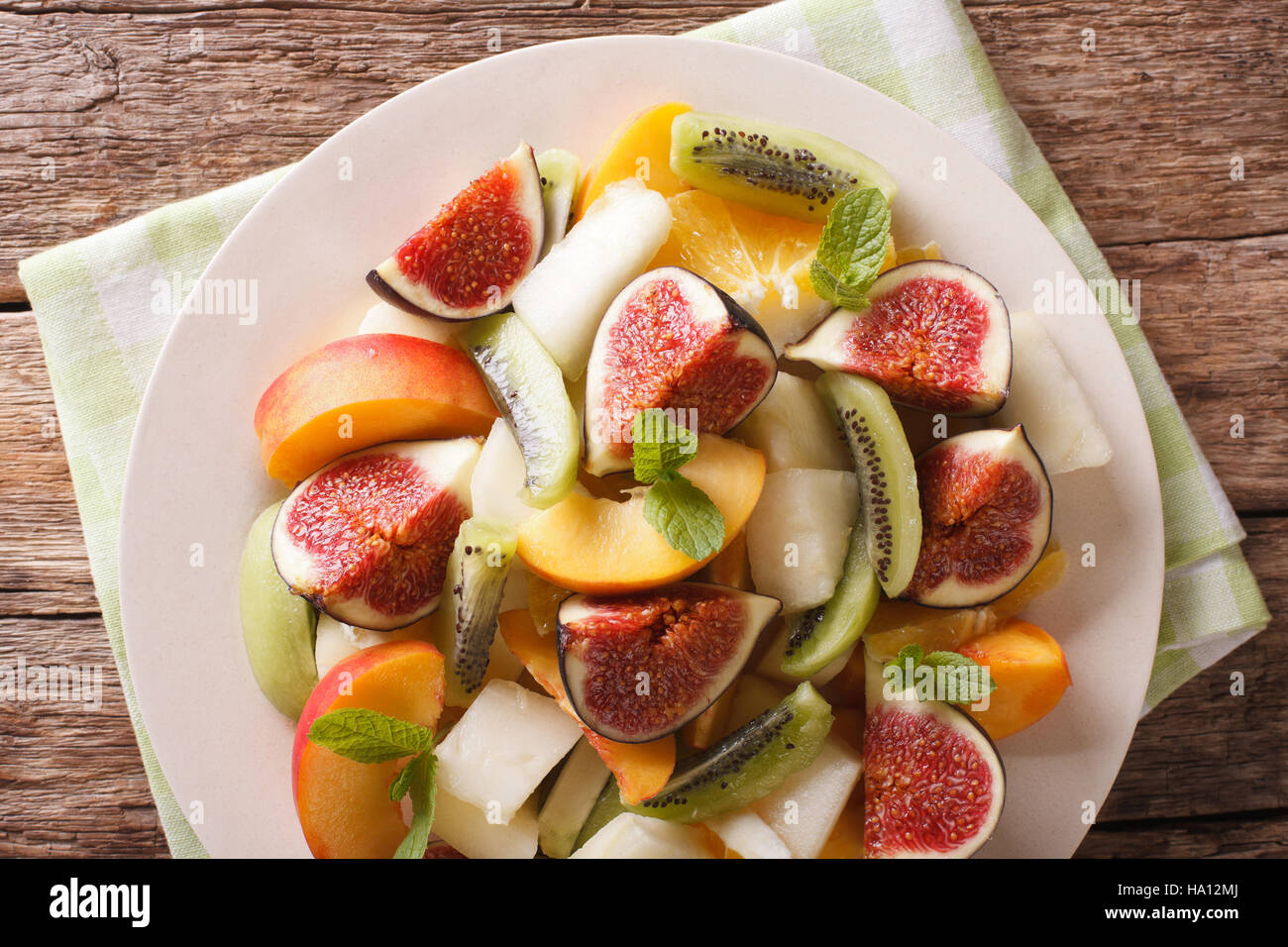 Sliced fresh fruit: figs, peaches, melons, kiwi and orange close-up on a plate. Horizontal view from above Stock Photo